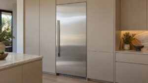 A tall built-in stainless refrigerator column set flush in a run of kitchen cabinetry