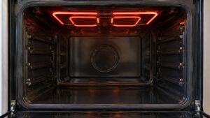 An empty built-in wall oven cavity with the upper heating element glowing softly and nothing else inside, no text or numbers visible